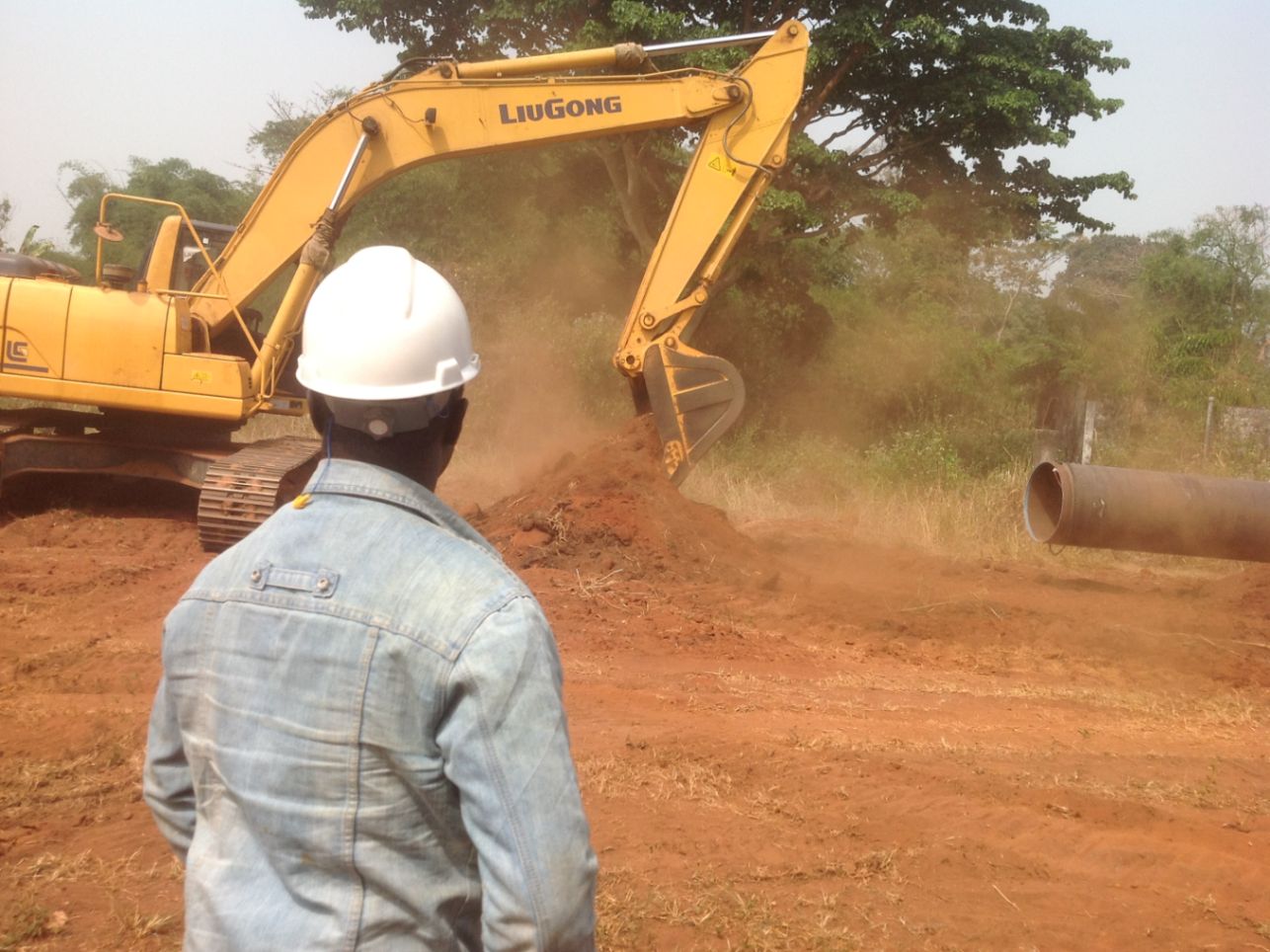Excavator clearing the pipeline route as an Olett supervisor watches