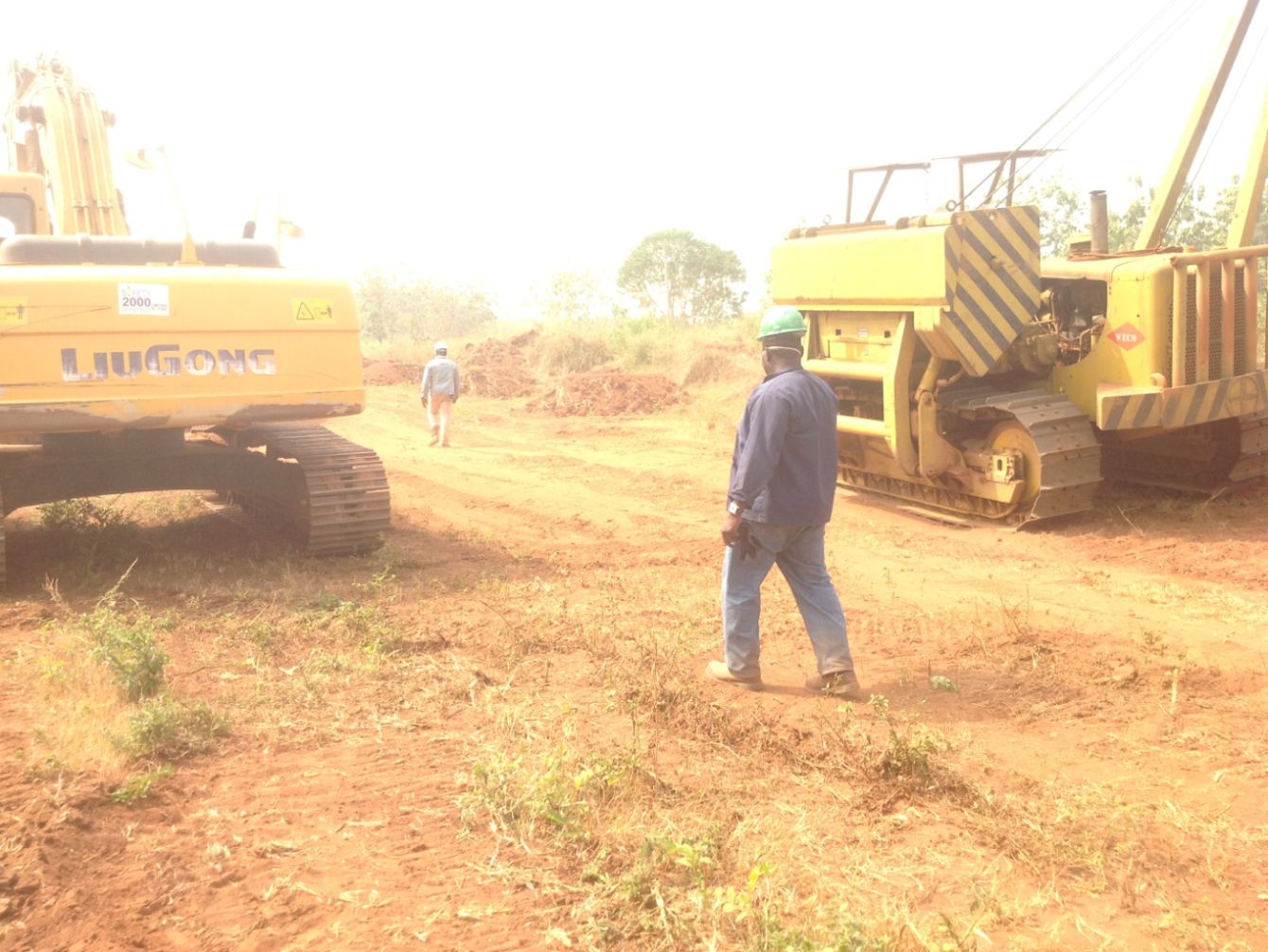 Site engineer walking the right of way between excavator and pipelayer